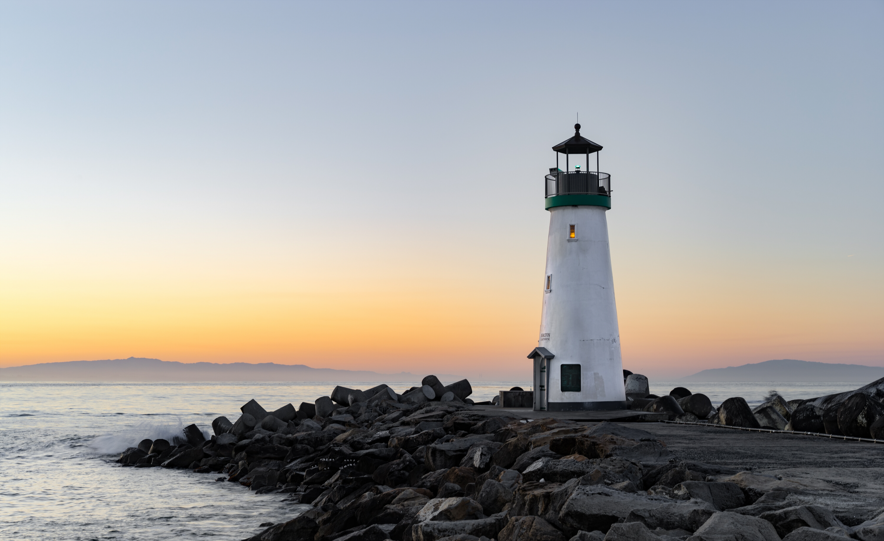 A lighthouse on a rocky cliff at sunset